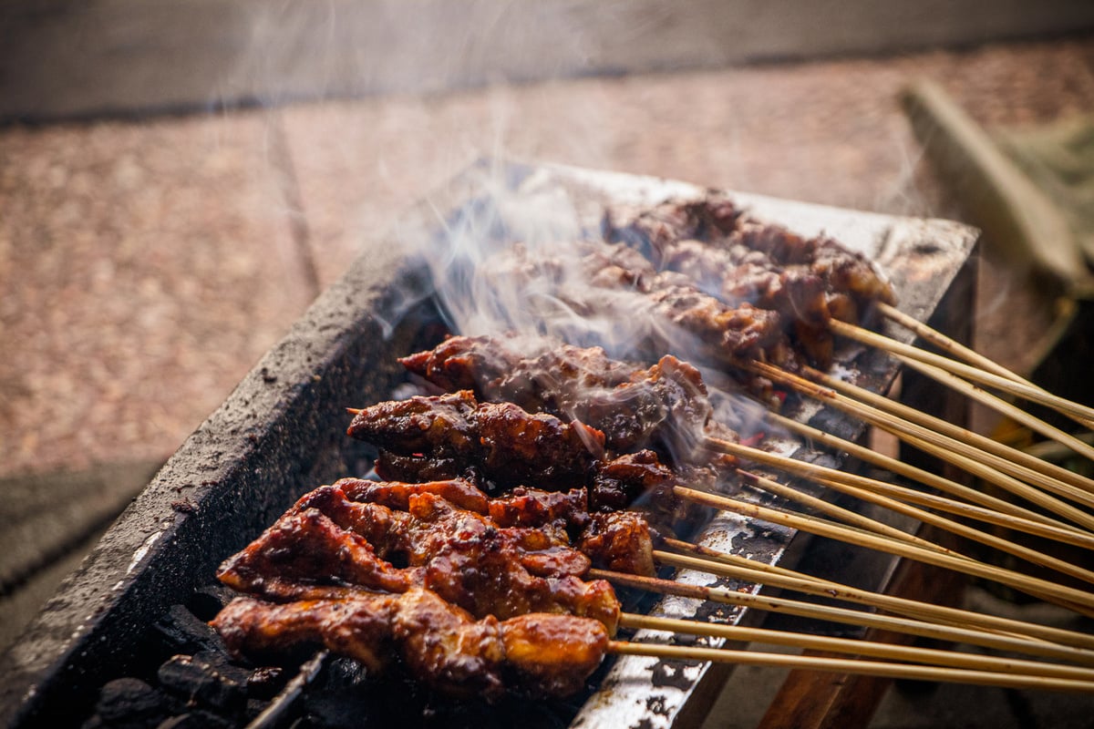 Chicken satay being grilled over hot coals